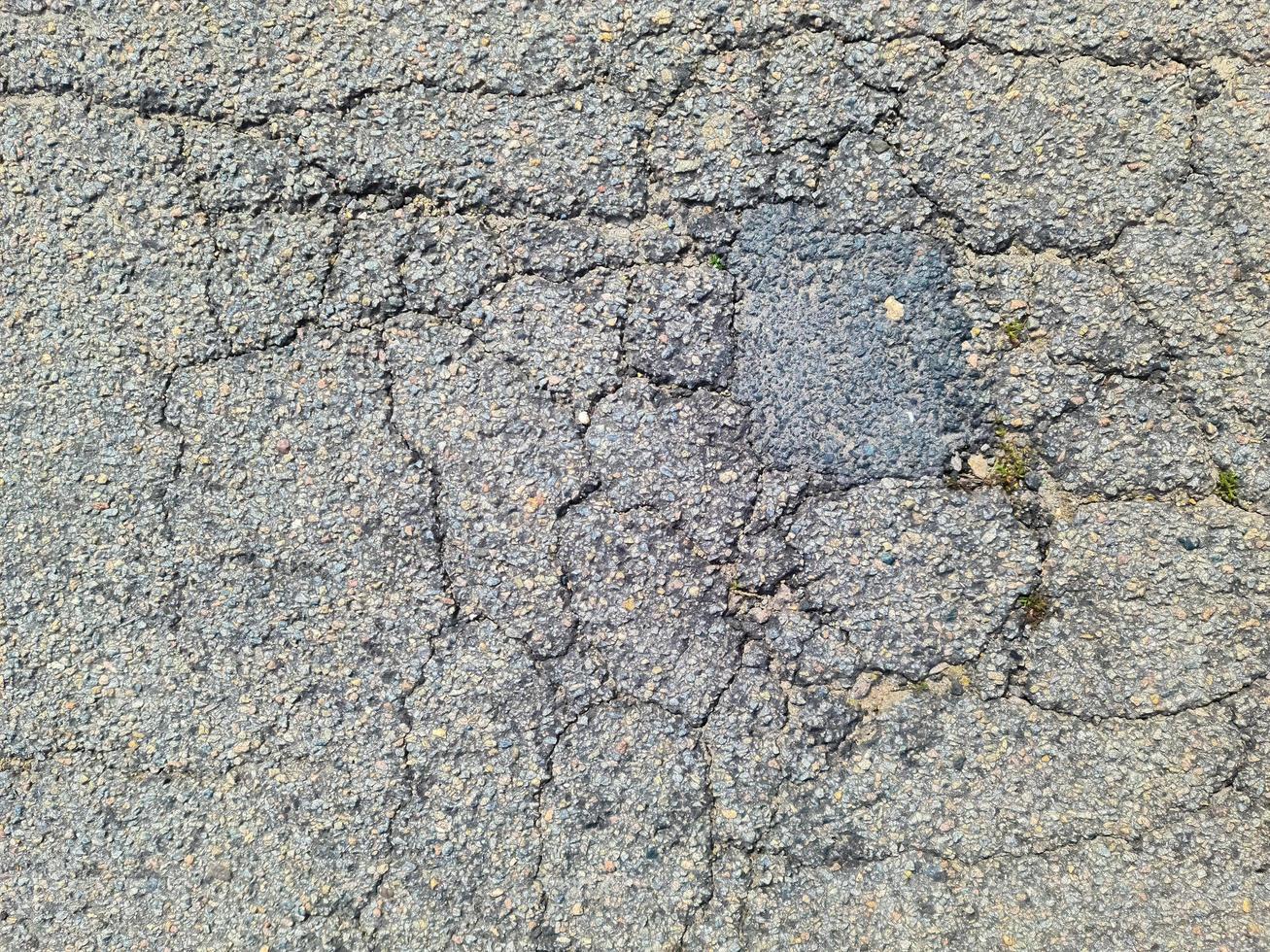 Asphalt surfaces of damaged streets and roads with cracks in a close up. photo