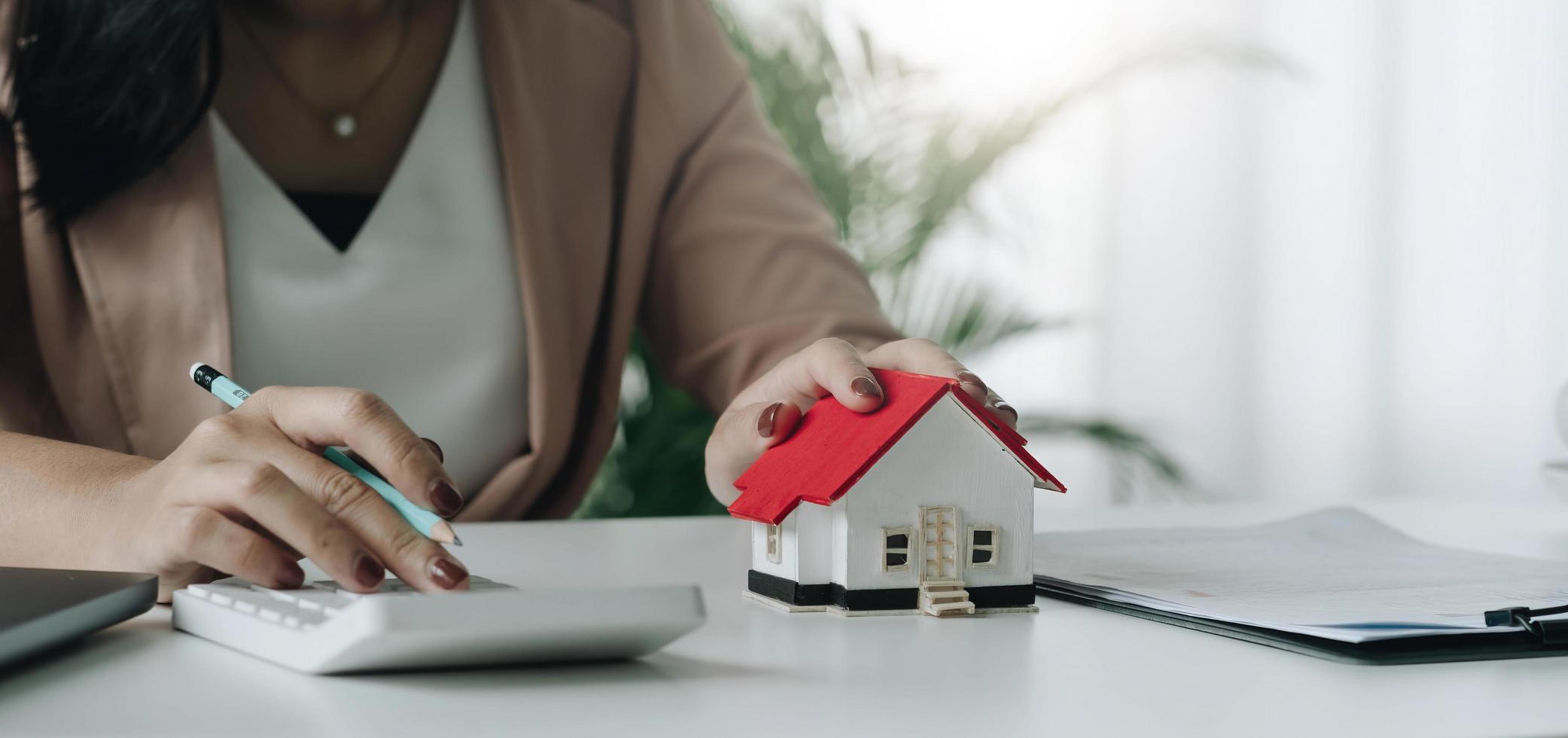 mujer de negocios con modelo de casa haciendo finanzas y calculando el costo de la inversión inmobiliaria y en otro sistema fiscal. concepto de banca de contabilidad de financiación empresarial foto