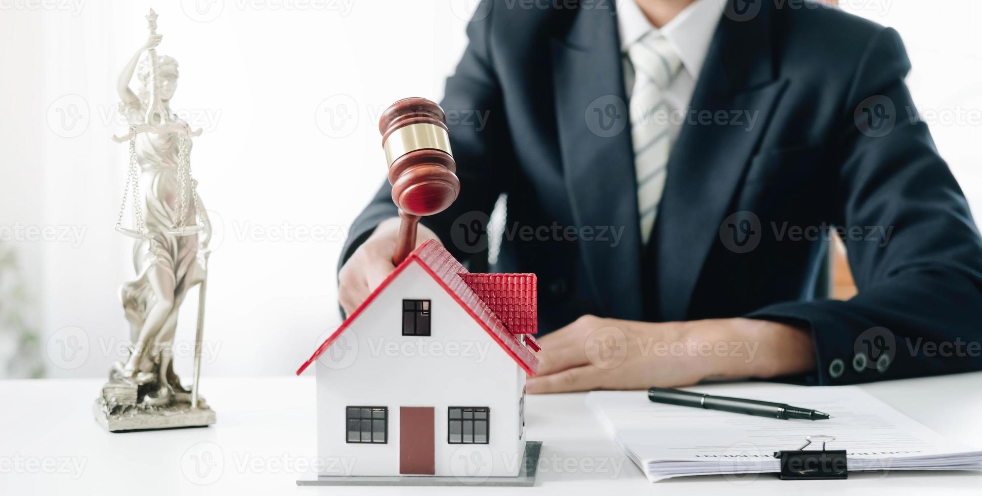 Businessman hand hold old wood Judge hammer with Mini wood house model from model on wood table, Planning buy Real Estate, Planning to buy property and Choose the best, financial liabilities concept. photo