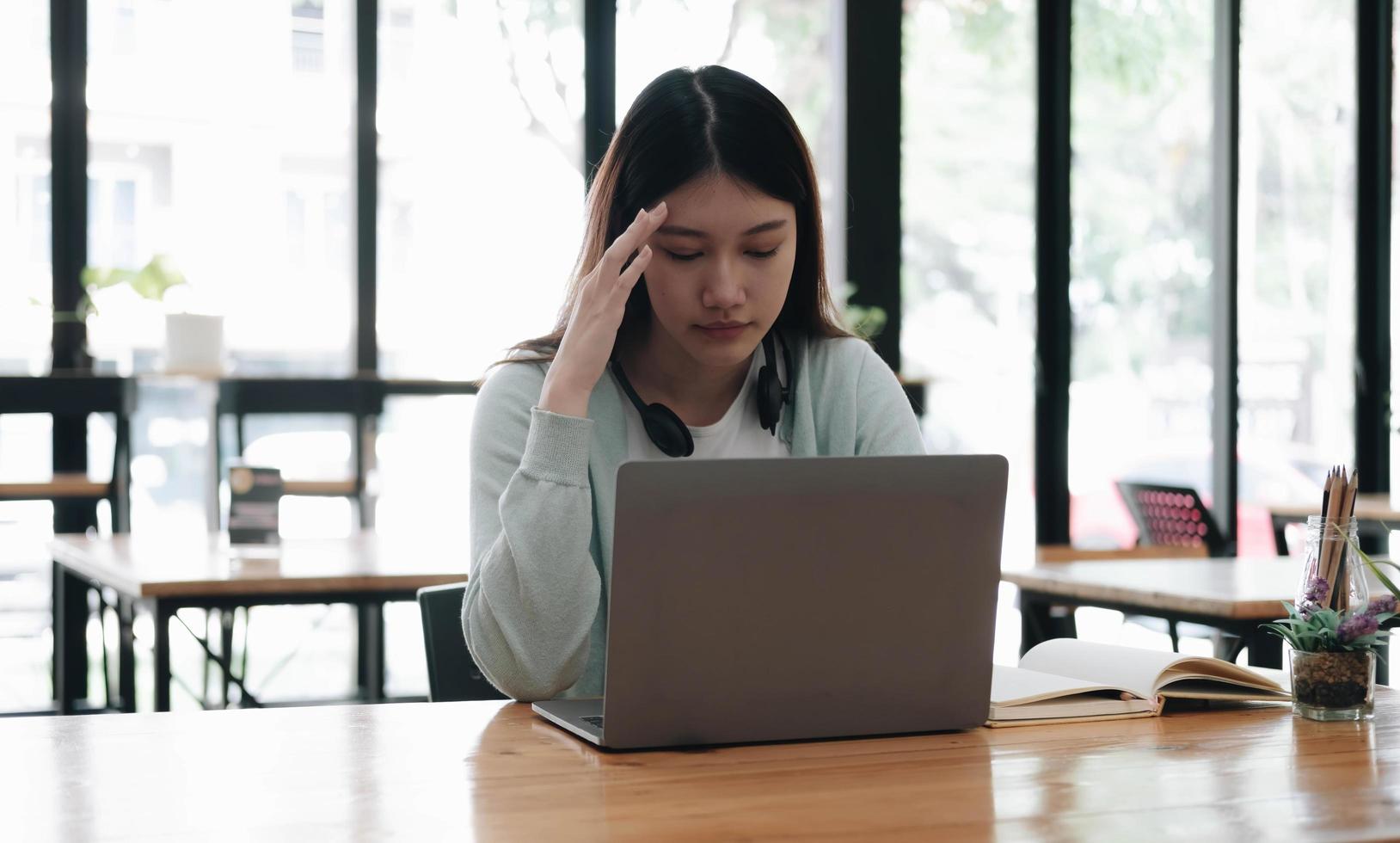 Serious focused Asian student using laptop in kitchen, looking at screen with attention and concentration, watching learning webinar, virtual training, video course, studying from home photo