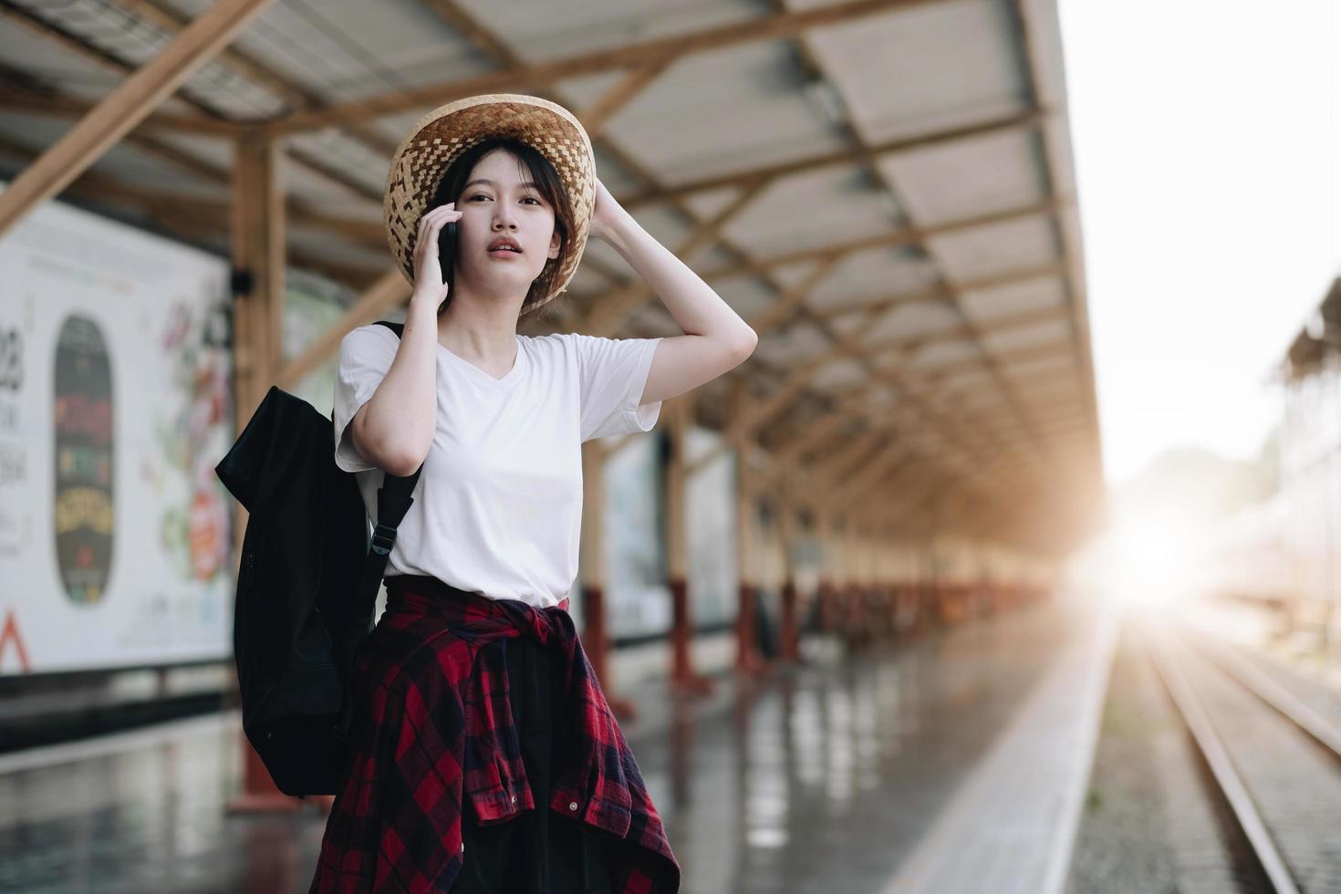 joven viajera que busca un amigo que planee un viaje en la estación de tren. concepto de estilo de vida de verano y viajes foto