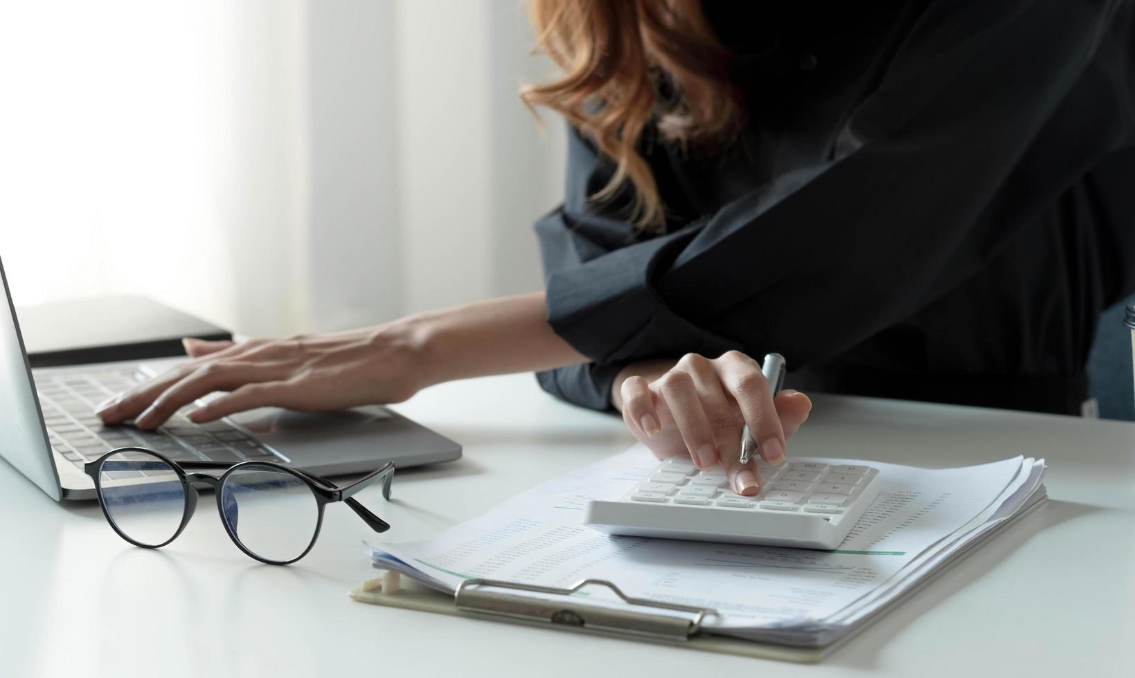 Close up Businessman using calculator and laptop for calaulating finance, tax, accounting, statistics and analytic research concept photo