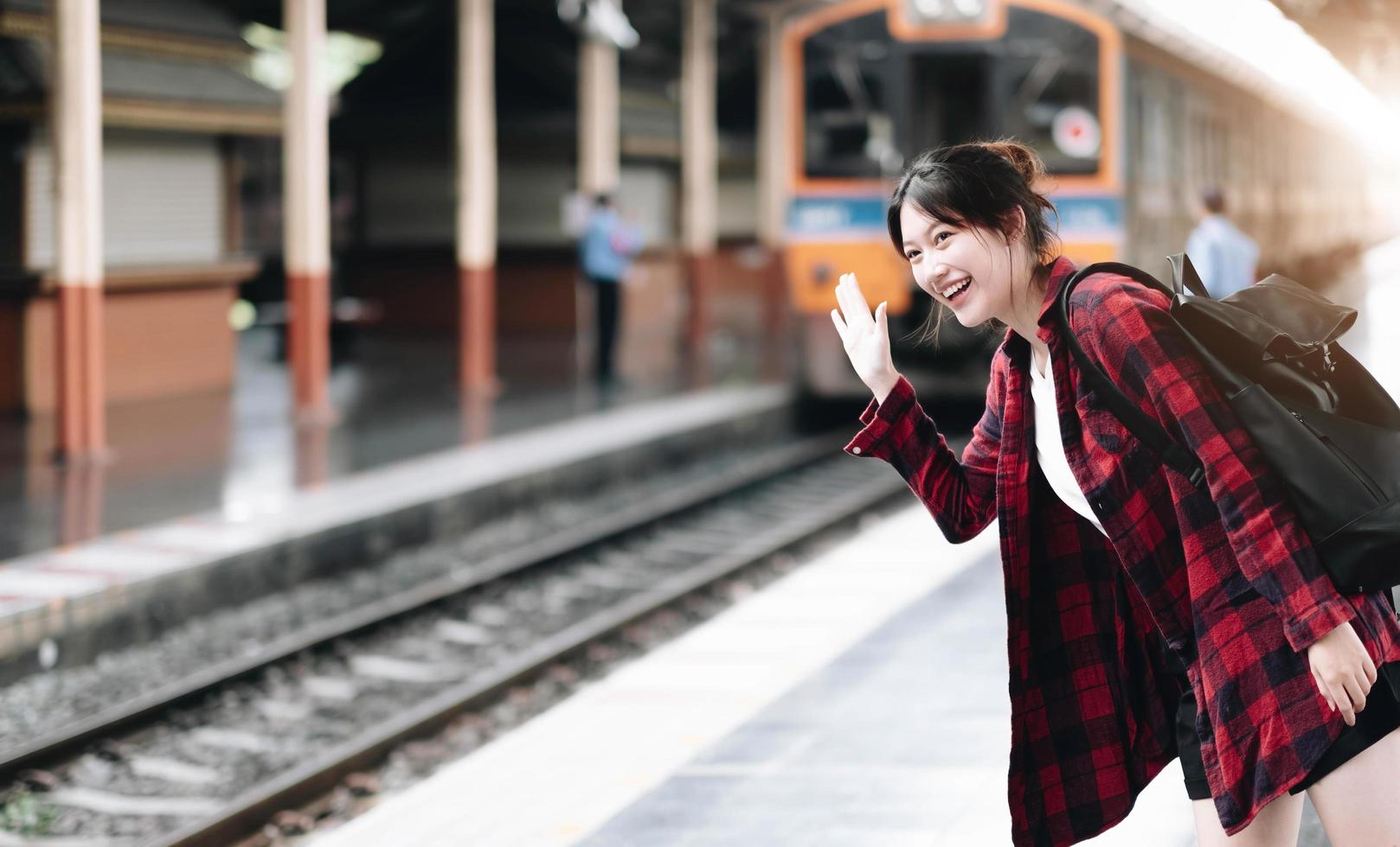 joven viajera que busca un amigo que planee un viaje en la estación de tren. concepto de estilo de vida de verano y viajes foto