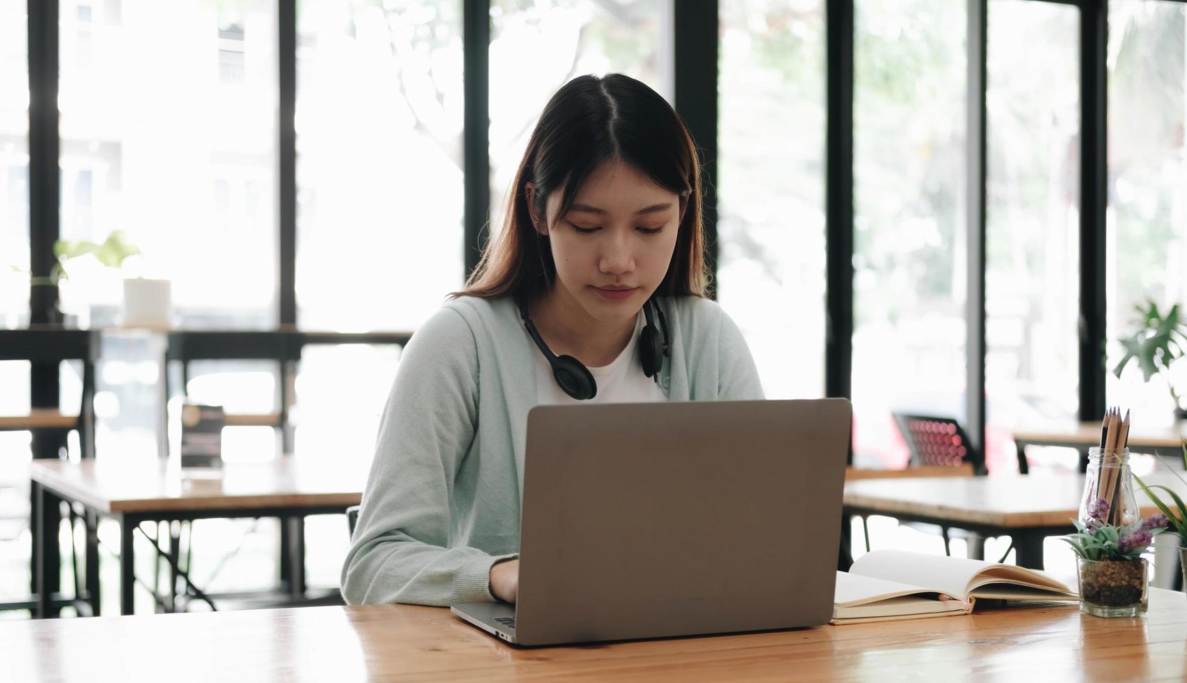 Serious focused Asian student using laptop in kitchen, looking at screen with attention and concentration, watching learning webinar, virtual training, video course, studying from home photo