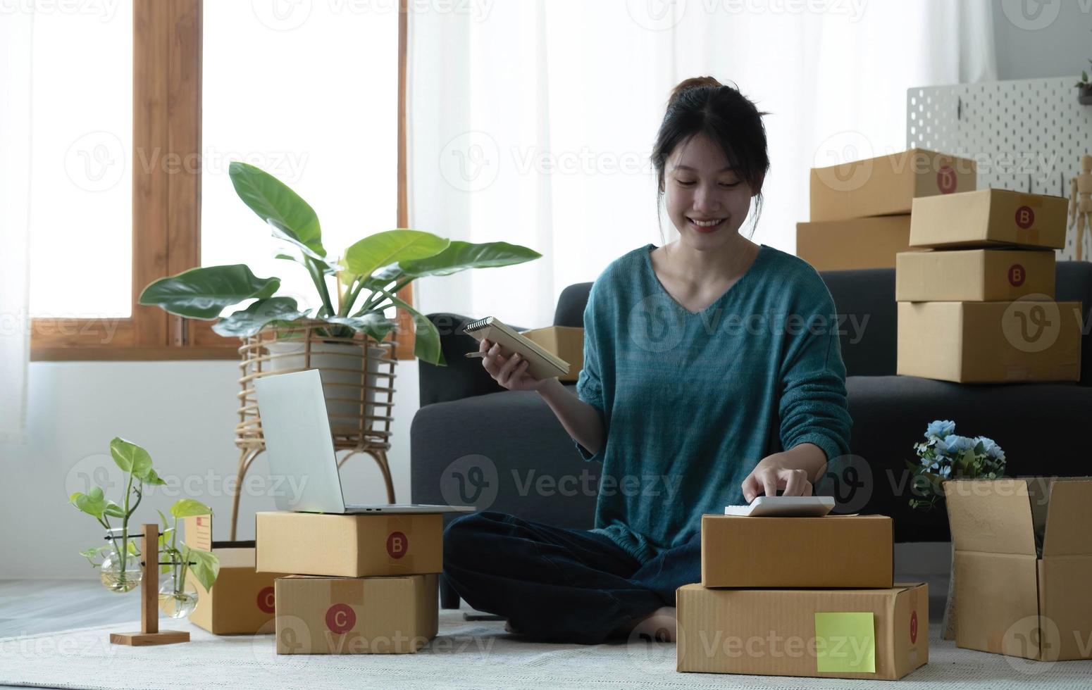 Asian women write note of orders of goods with a smiling face in concept of sme, e-commerce business photo