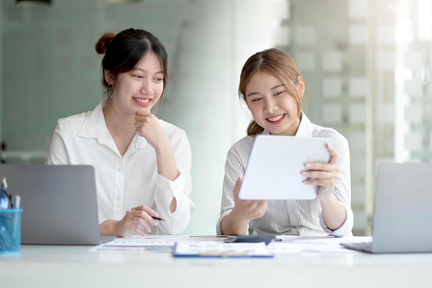 dos jóvenes empresarias asiáticas discuten con la presentación de una nueva idea de proyecto de inicio, analizan la planificación y las estadísticas financieras y el mercado de inversión en la oficina. foto