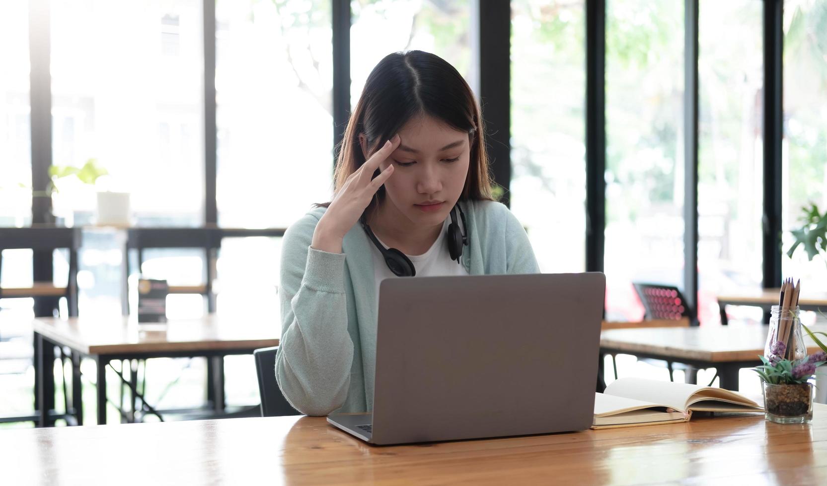 Serious focused Asian student using laptop in kitchen, looking at screen with attention and concentration, watching learning webinar, virtual training, video course, studying from home photo