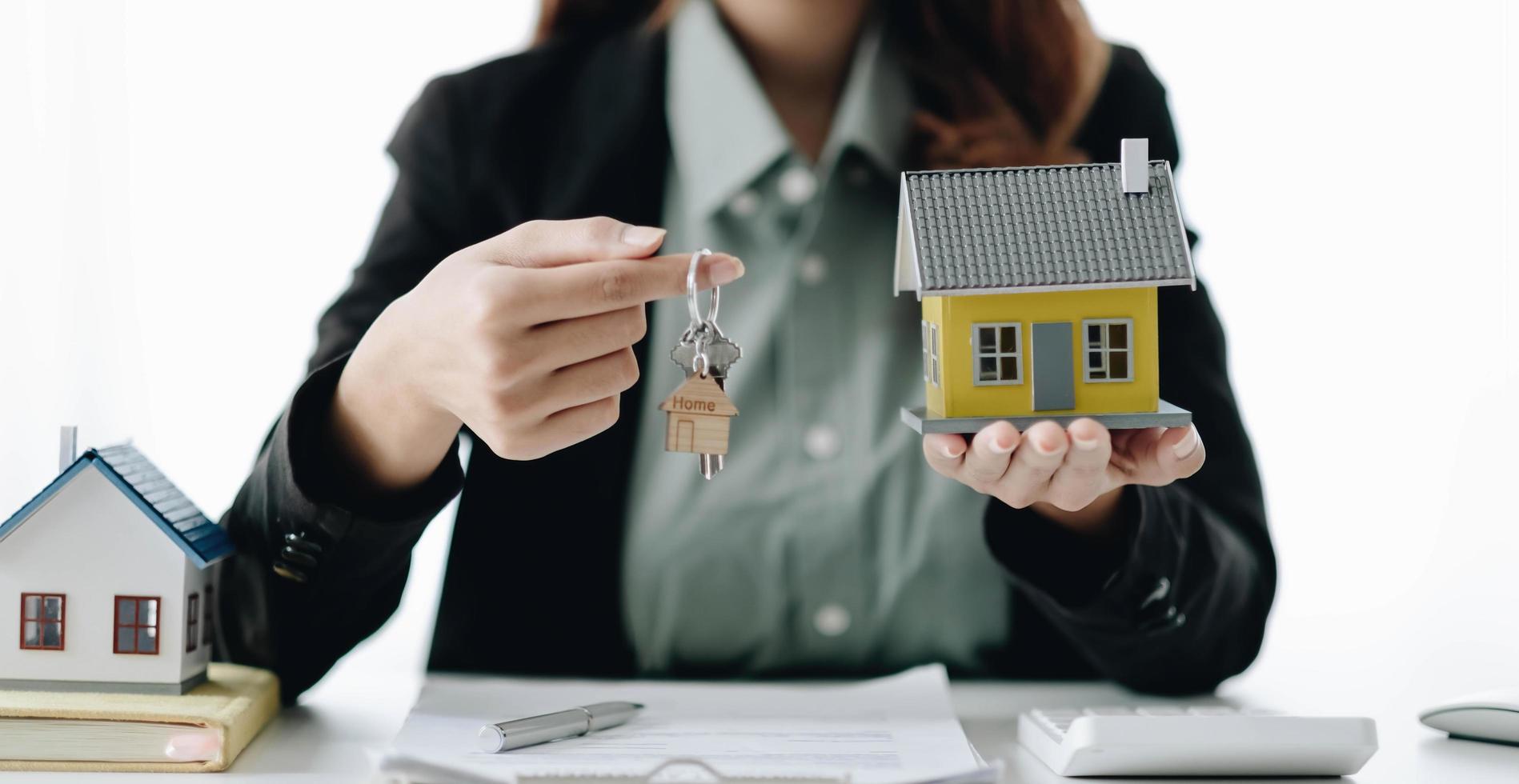 Estate agent are presenting home loan and sending keys to client after signing contract to rental house Insurance with approved property form. photo