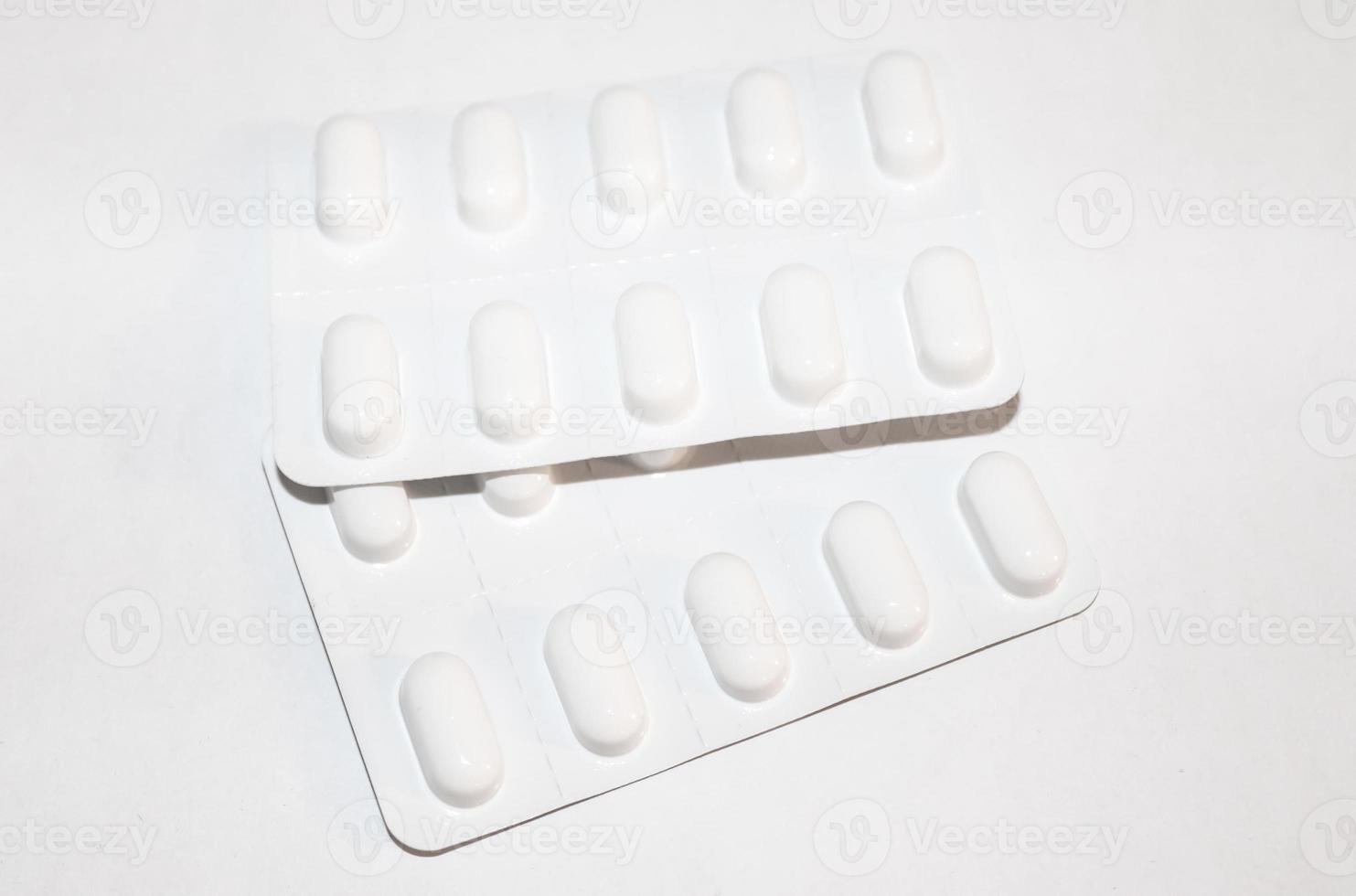 Pharmacy drugstore concept. Packs of white pills packed in blisters with copy space isolated on a white background. Focus on foreground, soft bokeh. photo