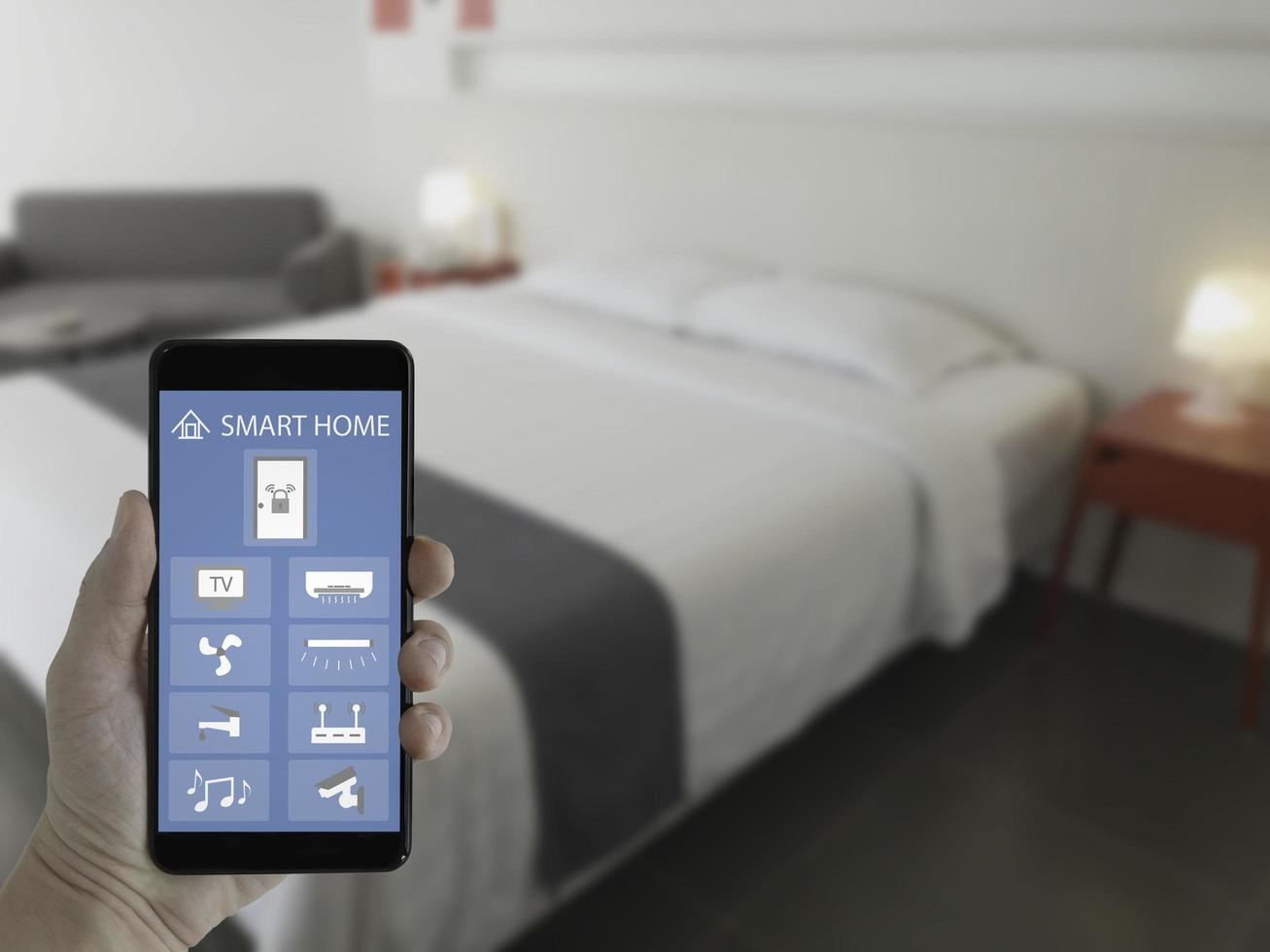 Smart home technology applications on smartphone screen with blurred bedroom background. photo