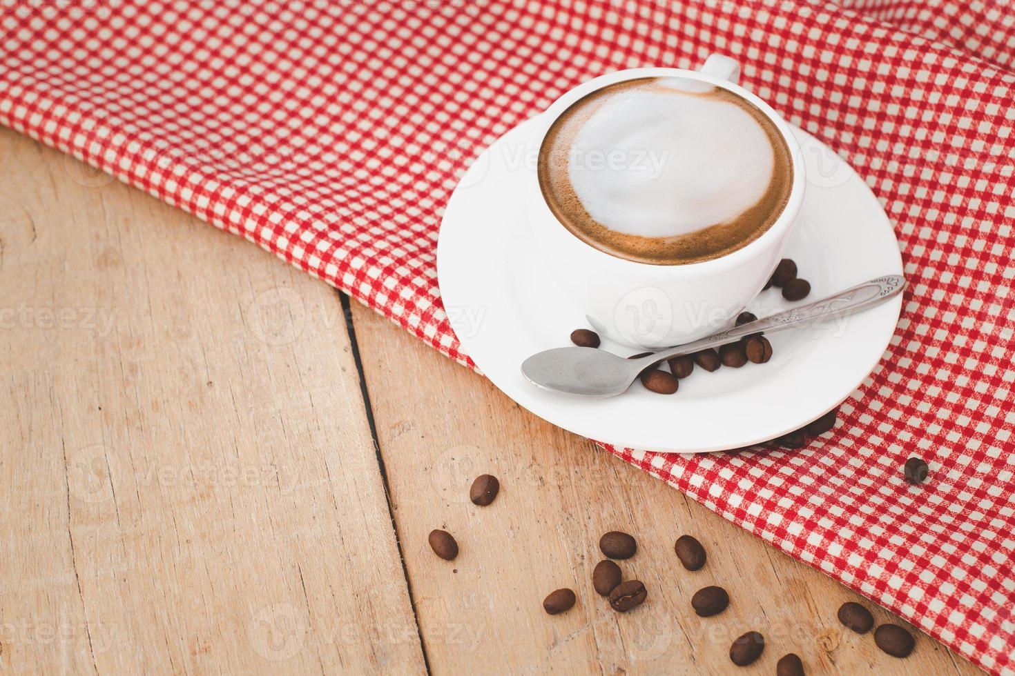 latte coffee in white cups and coffee beans with red patterned fabric on a wooden background.copy space. photo
