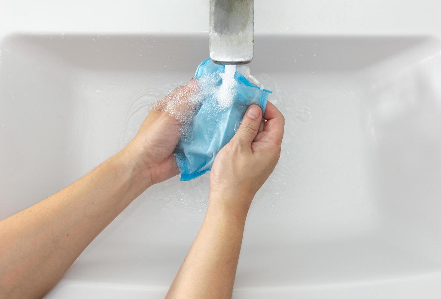 Hand of an Asian man washing a mask. Concept of cleaning a mask. photo