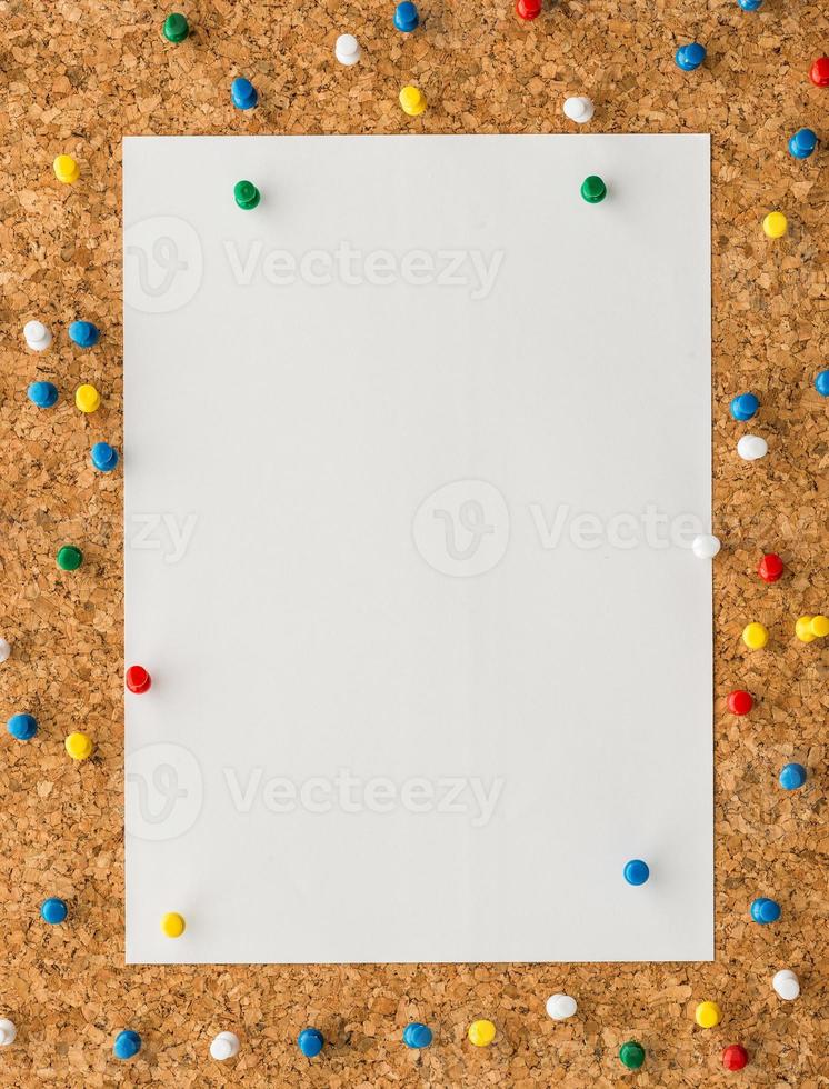 white paper note sheet with blue push pin on cork board photo