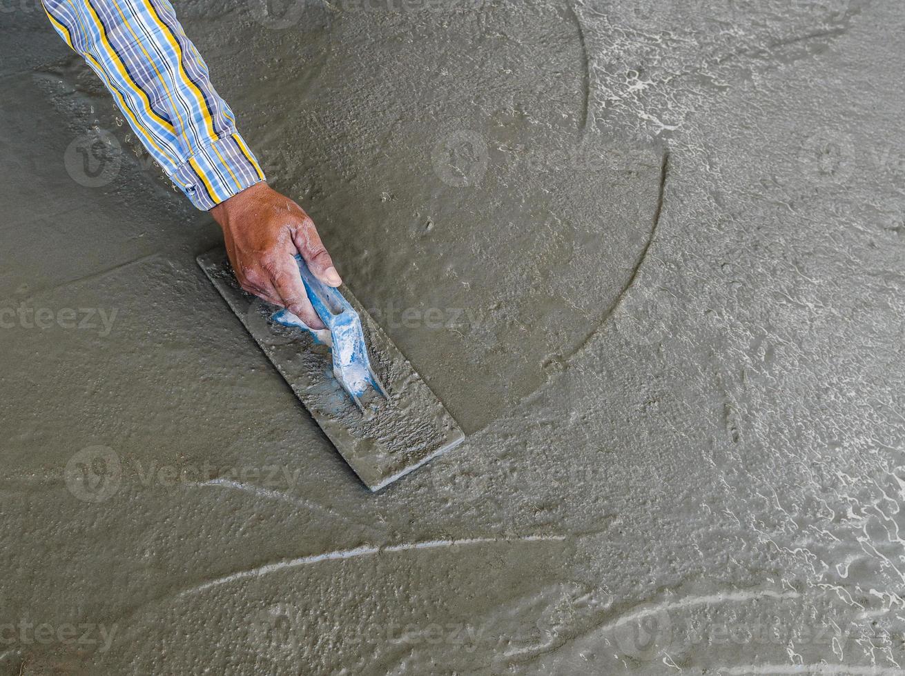 hand using trowel to finish wet concrete floor photo