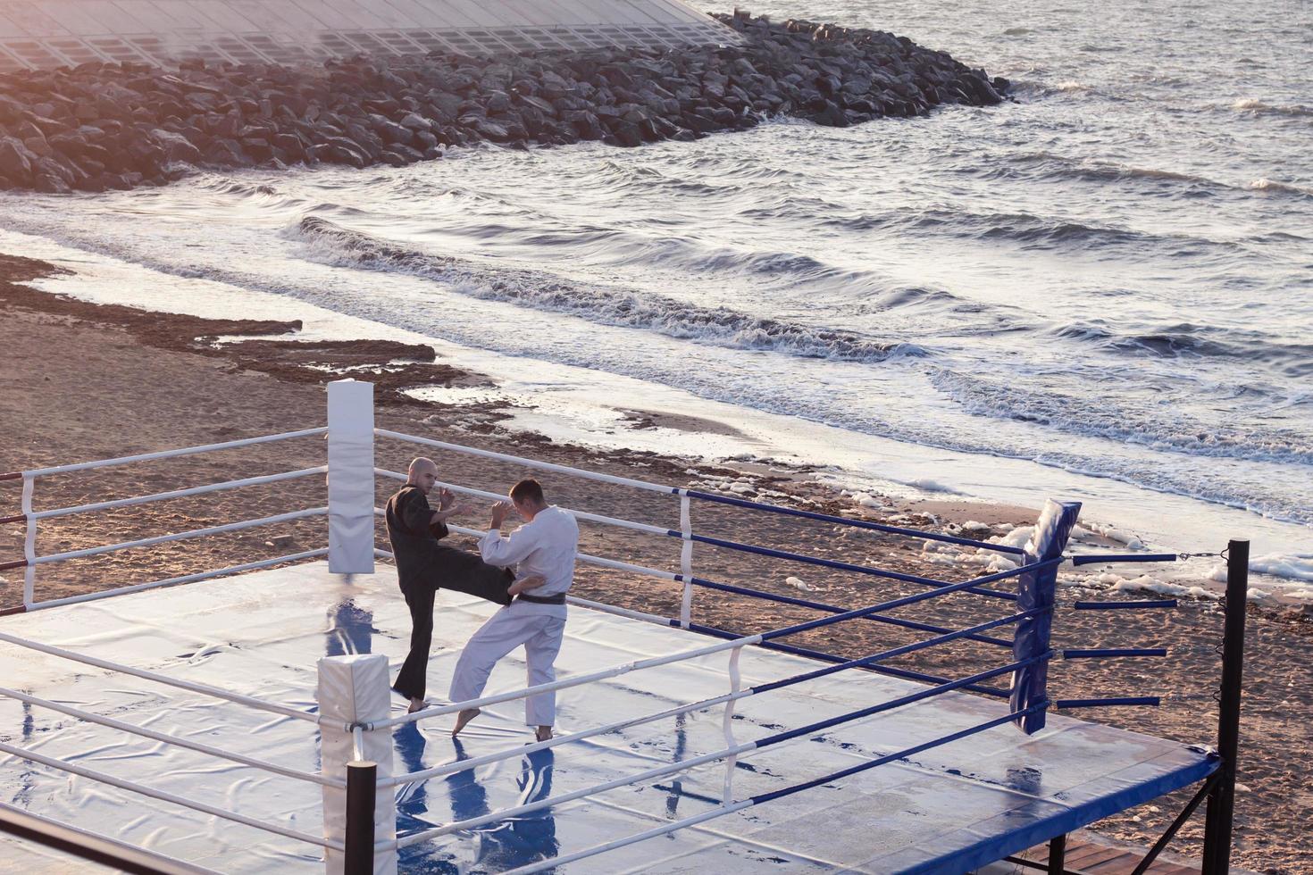 karate fighters are fighting on the beach boxing ring in morning photo