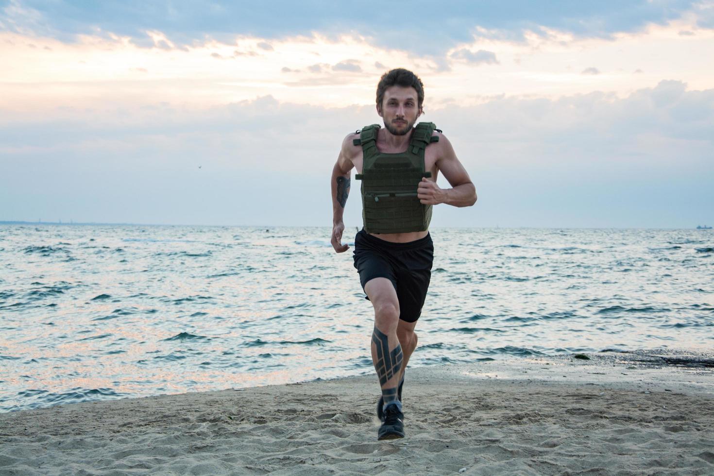 joven atleta barbudo entrenando al aire libre con chaleco ponderado, ejercicio con portador de placa militar foto