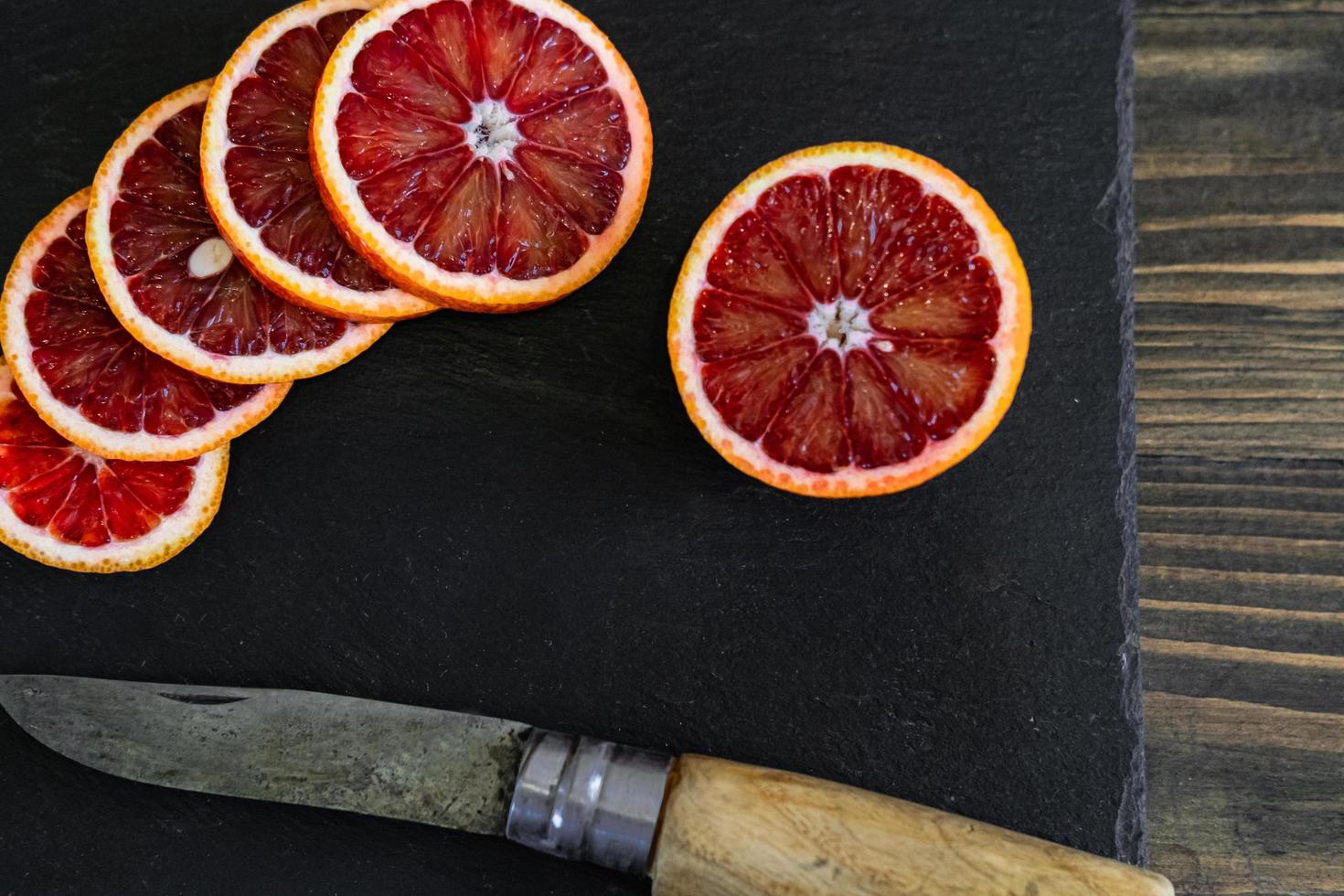 sliced sicilian or bloody oranges on a black slate background photo