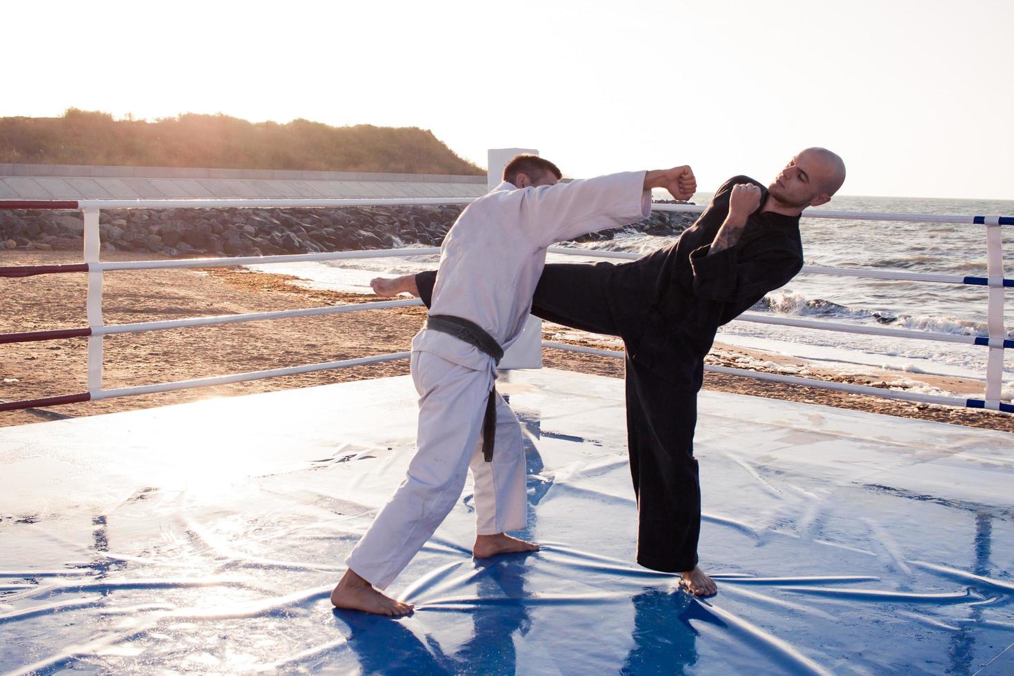 karate fighters are fighting on the beach boxing ring in morning photo