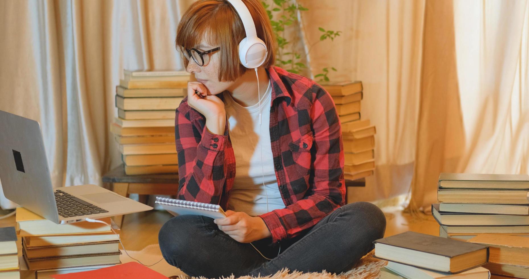 joven estudiante que estudia en casa con muchos libros y laptop foto