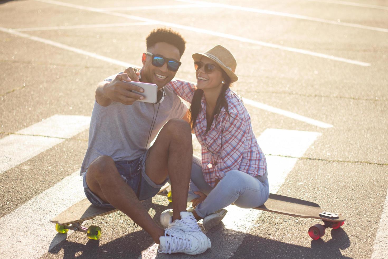Happy young couple riding skateboard during sunrise photo