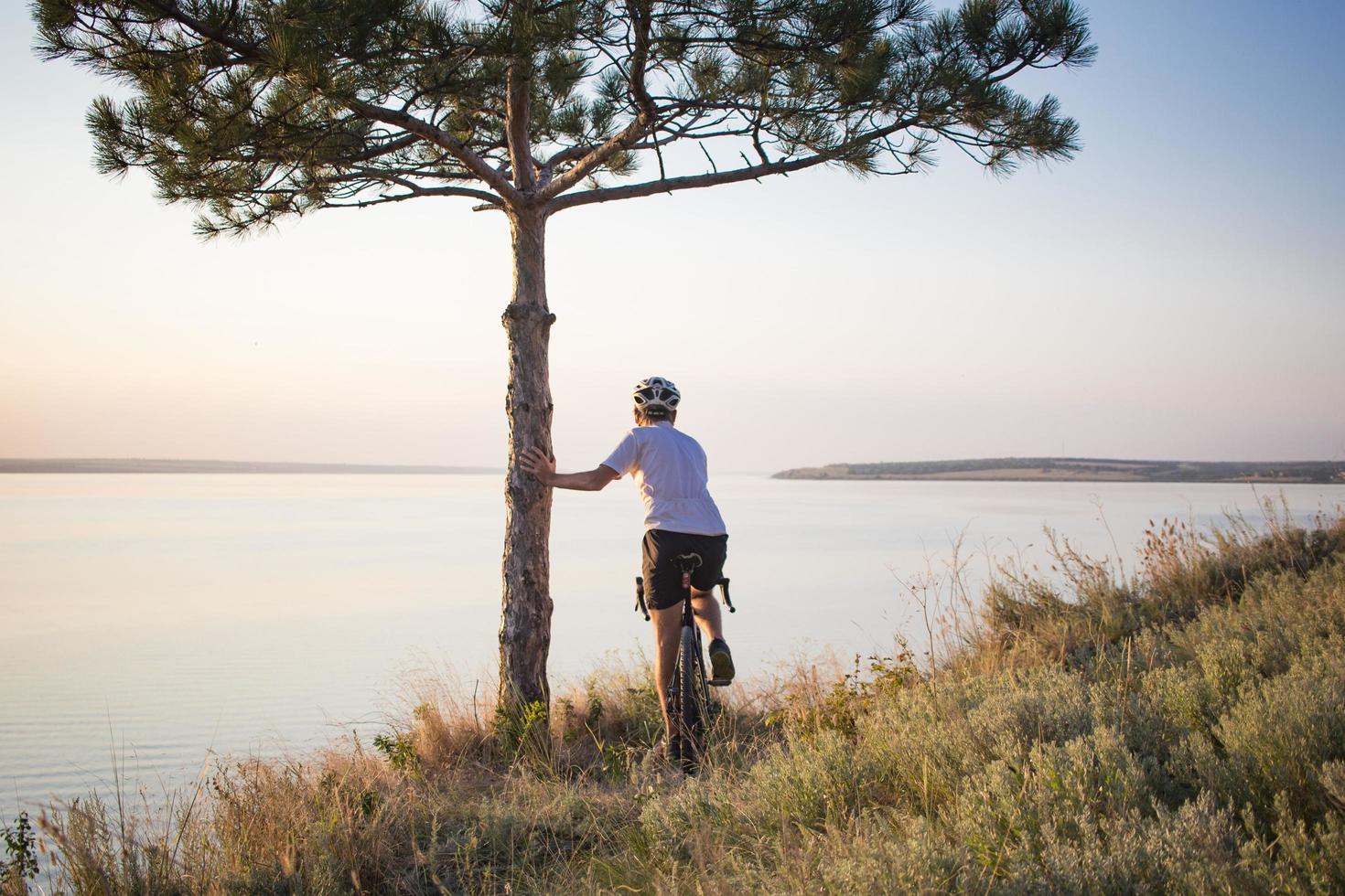 Bicycle rider on professional cyclocross bike ride downhill, pine and lake background photo