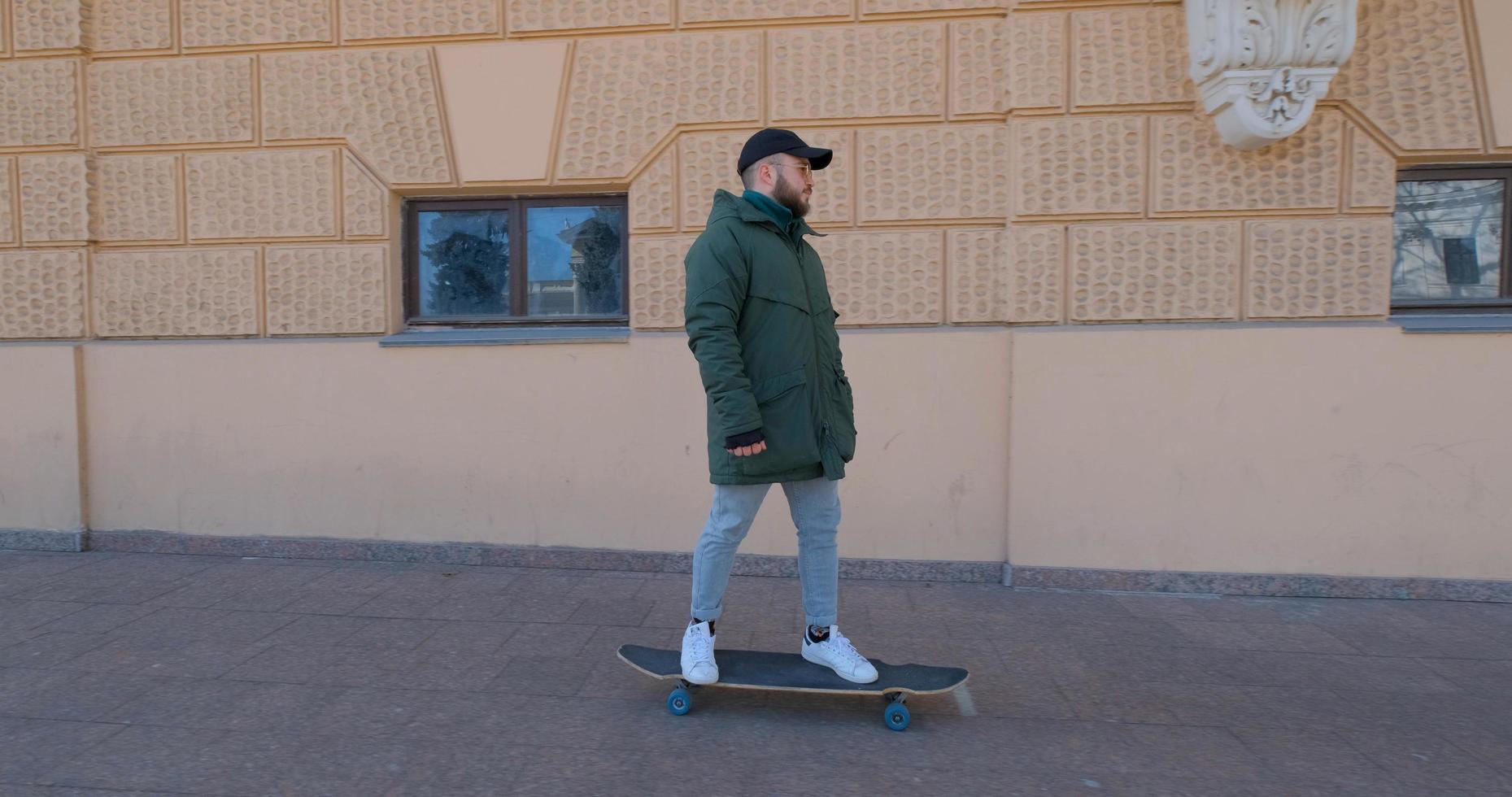 paseo masculino joven en longboard skate en las calles foto