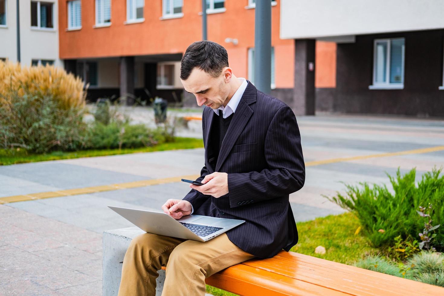 businessman work outdoors with laptop and cellphone photo