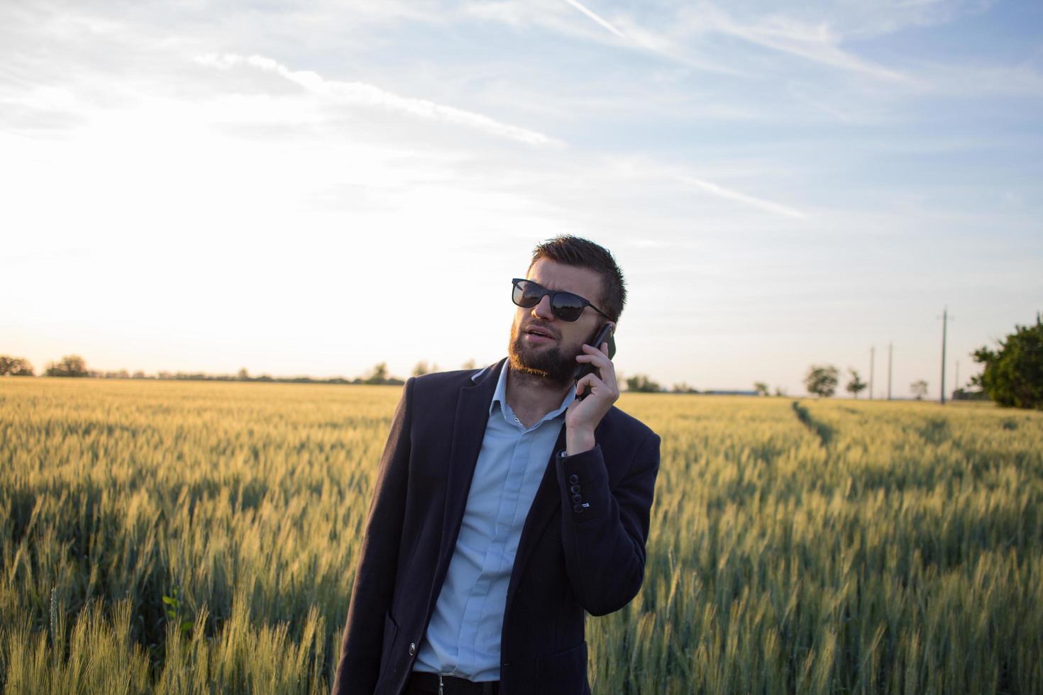 buisinessman in summer wheat fields using tablet during the sunset,man in suit with compact computer photo