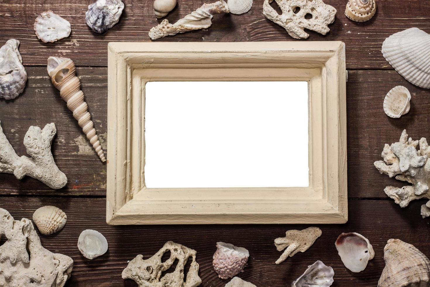 marco de fotos en blanco con conchas en la mesa de madera
