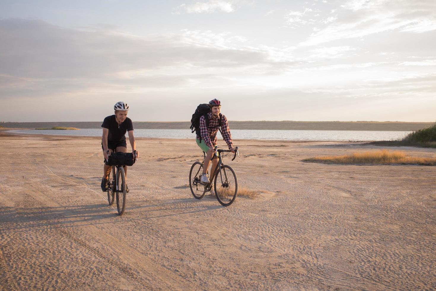 Two young male on a touring bicycle with backpacks and helmets in the desert on a bicycle trip photo