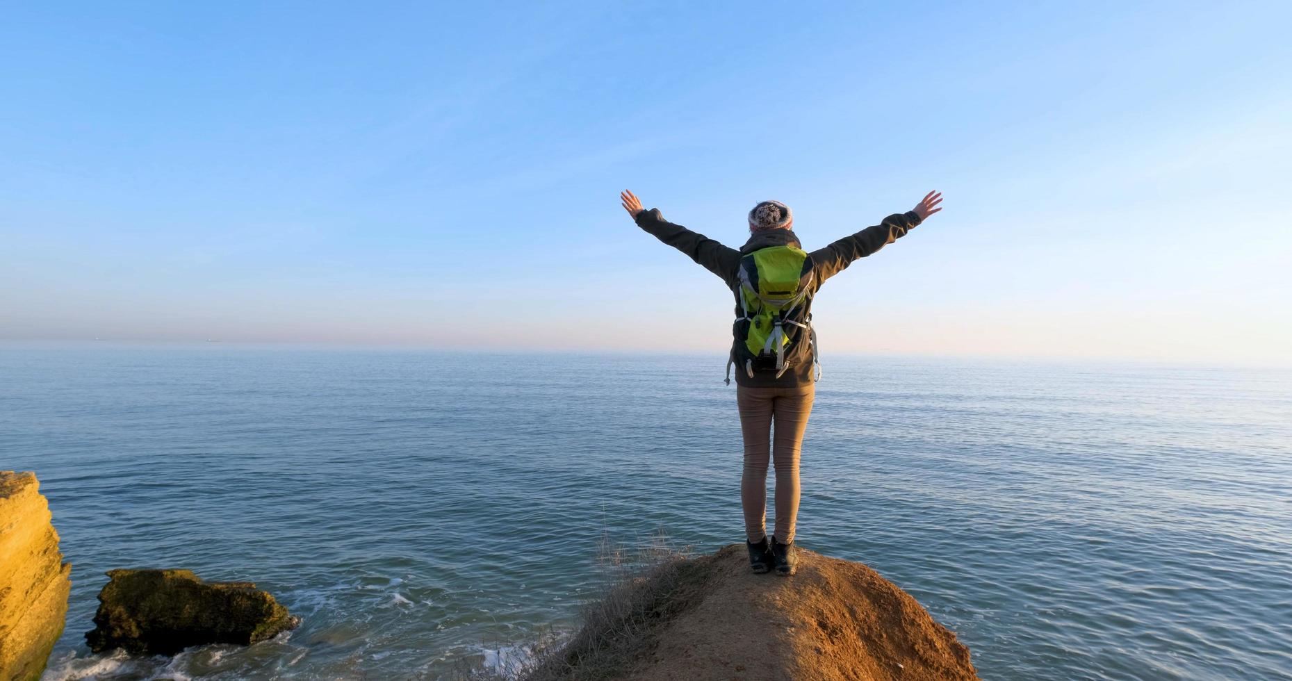 joven viajera con mochila y cámara de cine retro viaja en las montañas de otoño cerca del mar foto