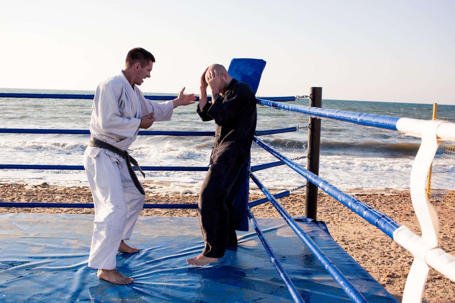 los luchadores de karate están peleando en el ring de boxeo de la playa por la mañana foto