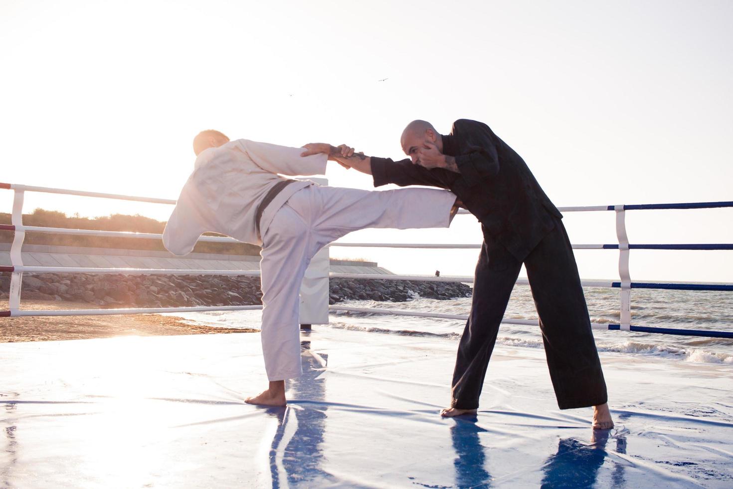 karate fighters are fighting on the beach boxing ring in morning photo