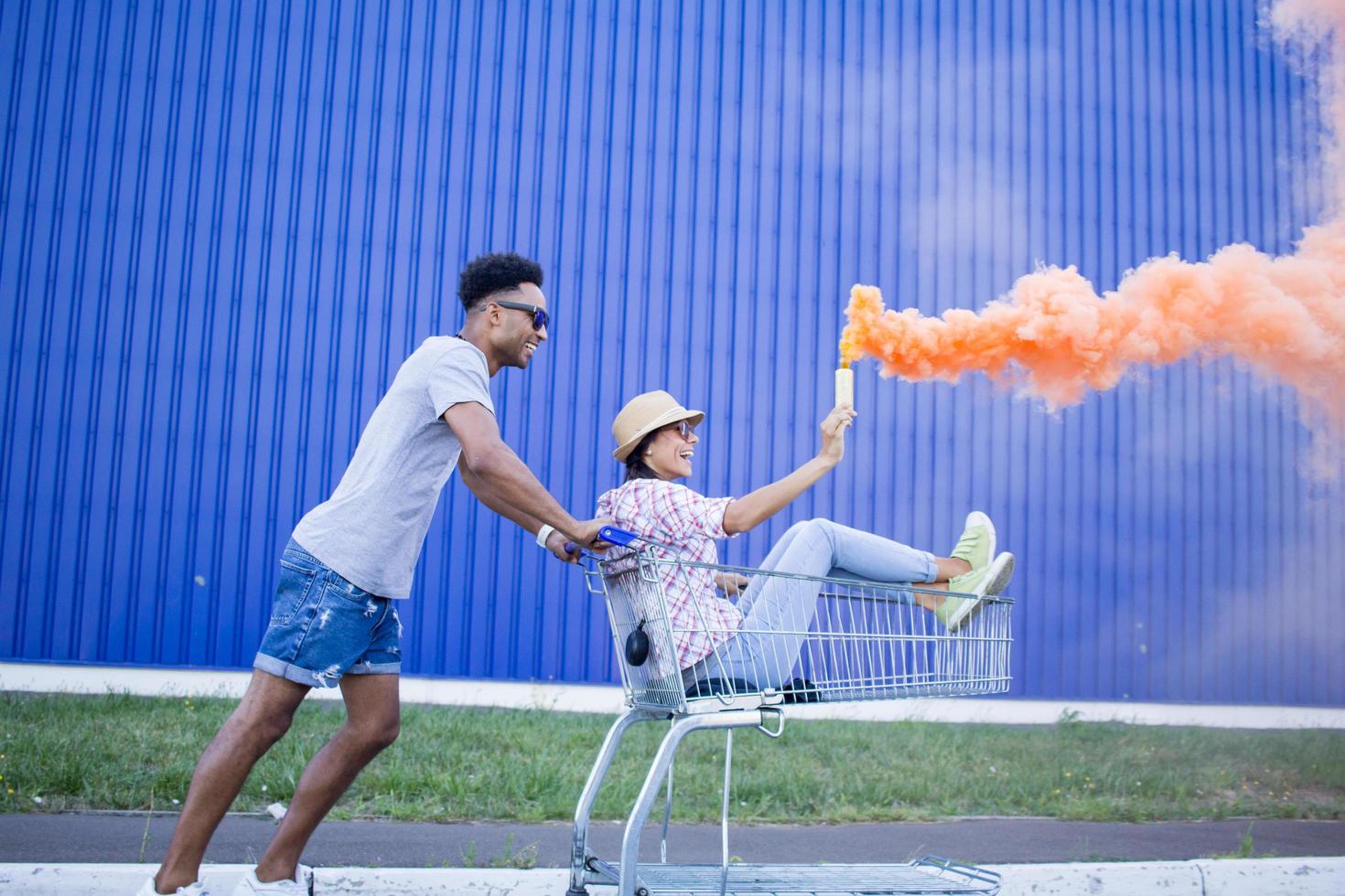 Happy young couple riding on trolley on empty mall parking , hipster friend have good time during shopping, couple in love riding on shopping cart photo