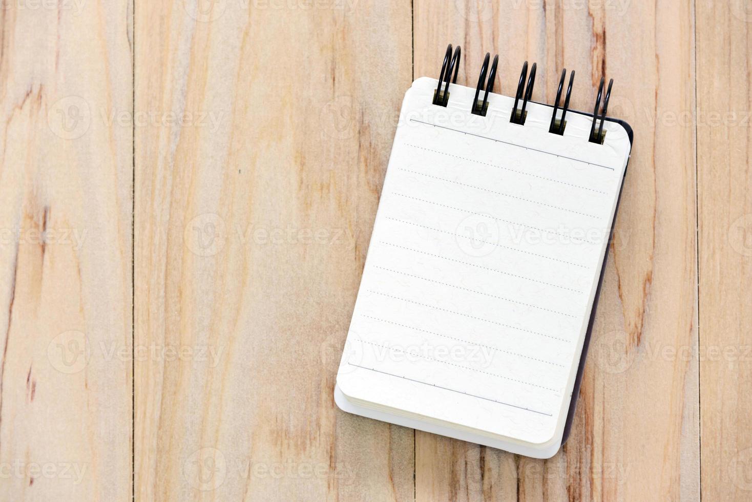 Mock up small note book paper or notepad on wood table for writing an information with copy space. view from above photo