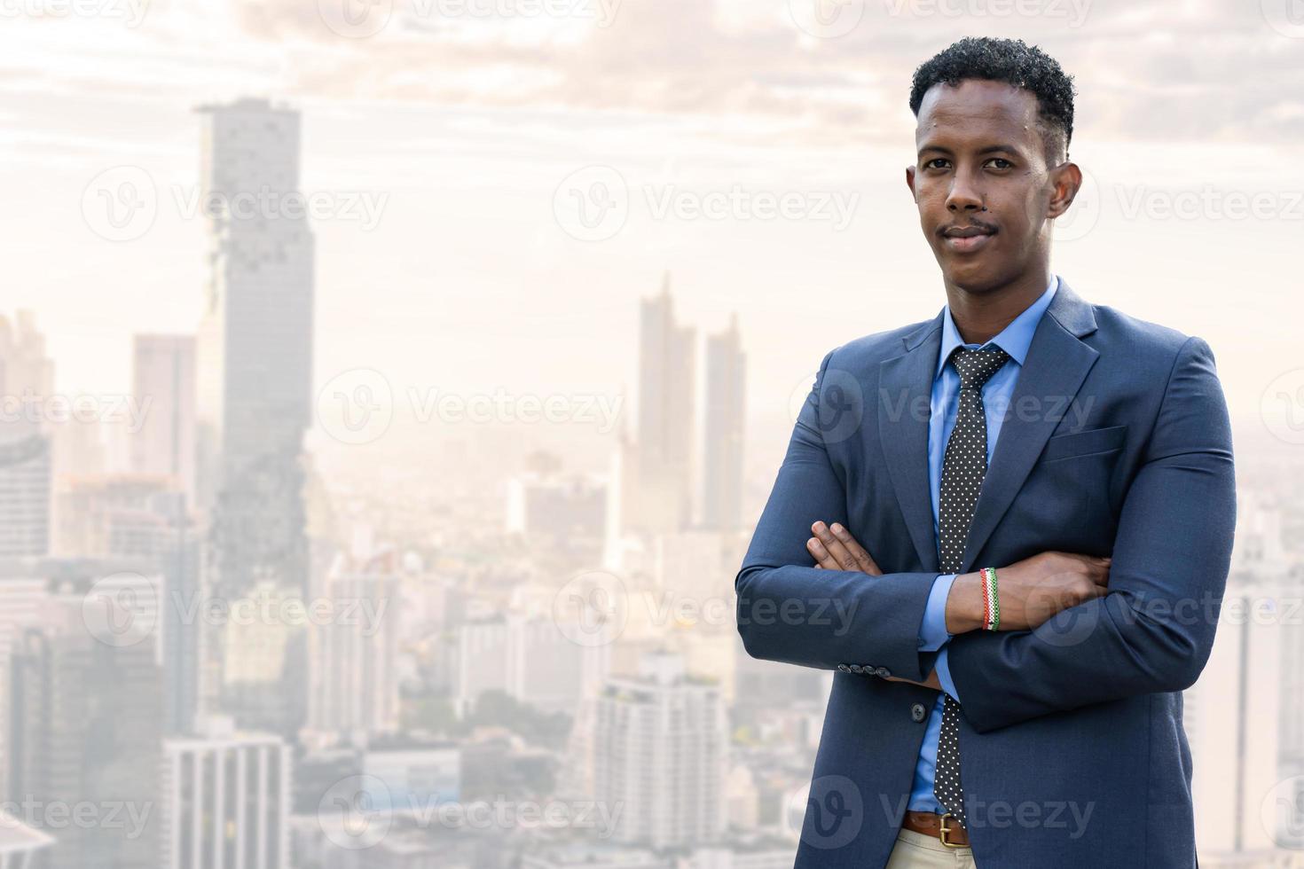 Business people in city. Portrait of an handsome businessman. Modern businessman. Confident young man in full suit and glasses while standing outdoors looking away with cityscape in the background photo