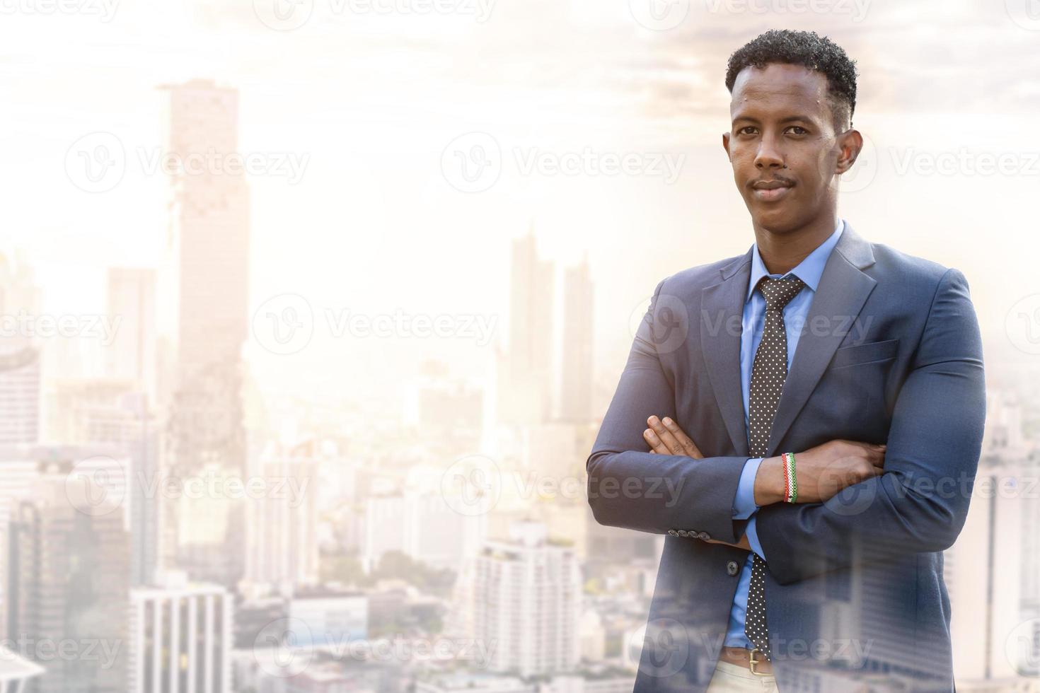 gente de negocios en la ciudad. retrato de un apuesto hombre de negocios. hombre de negocios moderno. joven seguro de sí mismo con traje completo y gafas mientras está de pie al aire libre mirando hacia otro lado con el paisaje urbano en el fondo foto