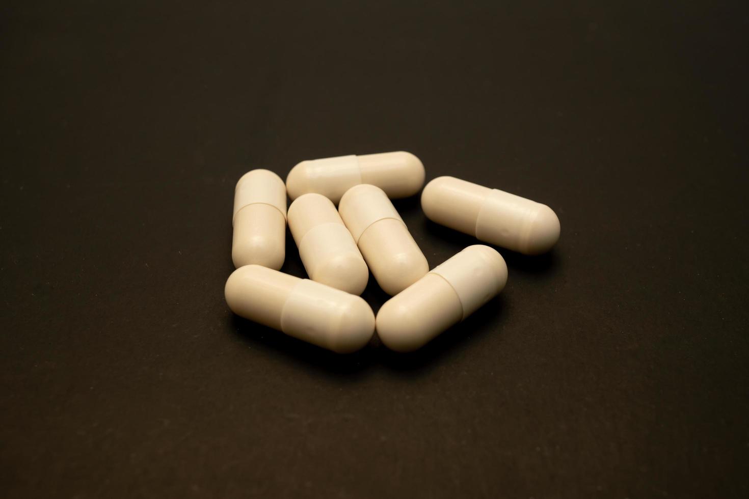 white capsule for patient on black paper. Prescription opioid oval pills. Opioid crisis. Medical white capsules isolated on a black background. Capsules for treatment photo