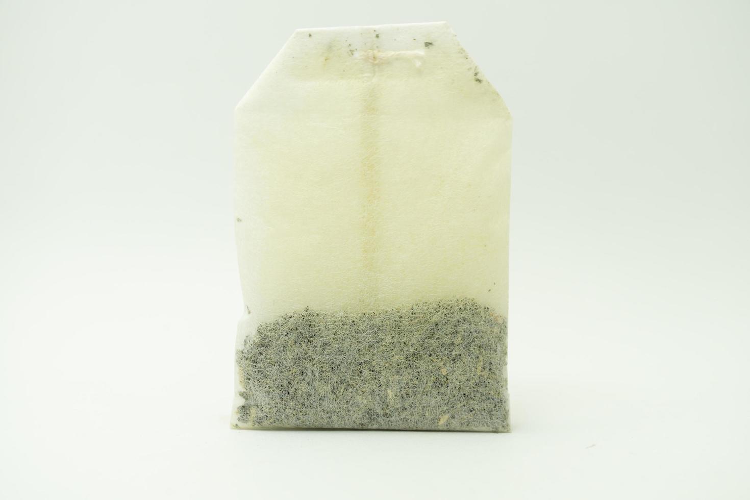 Teabag with green label. Isolated on white background. Close-up of tea bag. photo