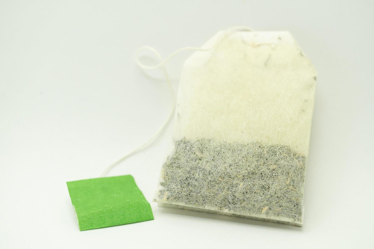 Teabag with green label. Isolated on white background. Close-up of tea bag. photo