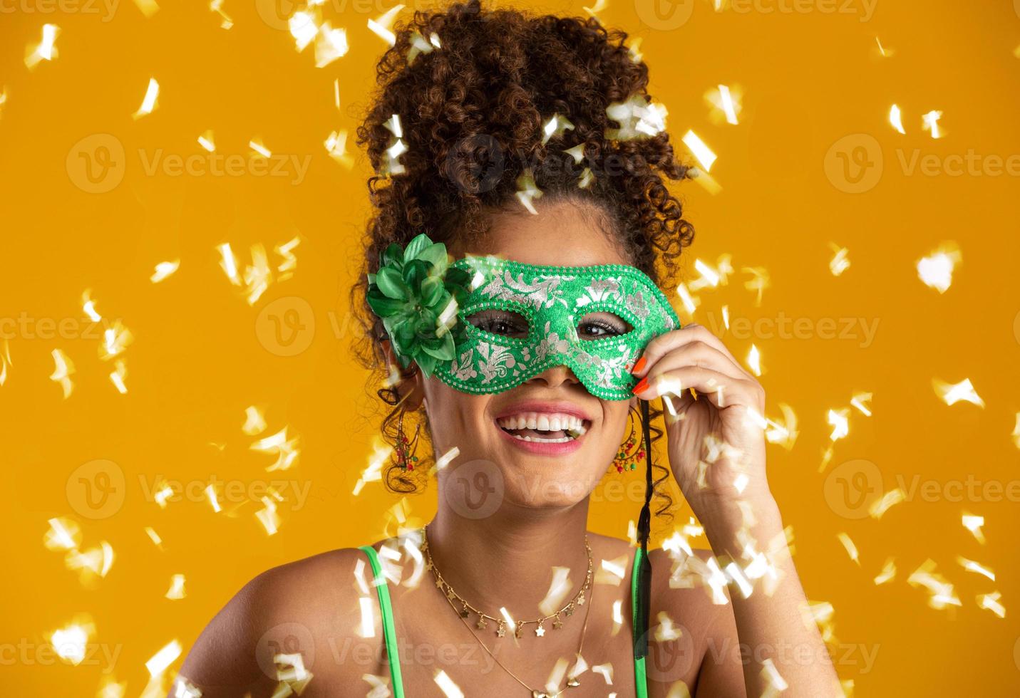 hermosa mujer vestida para la noche de carnaval. mujer sonriente lista para disfrutar del carnaval con una colorida máscara y confeti. foto