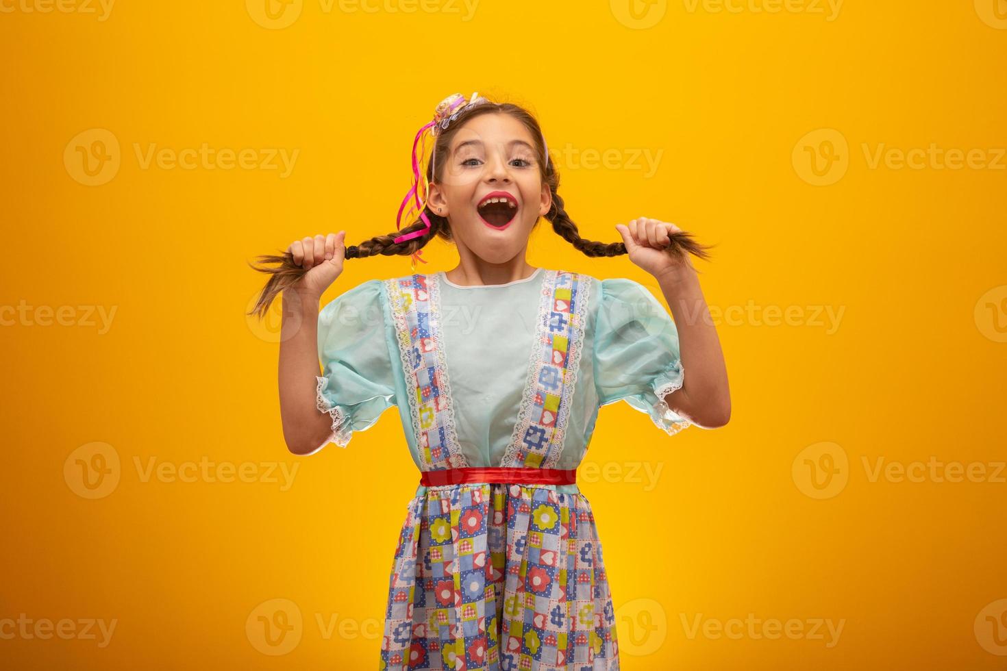 Child in typical clothes of famous Brazilian party called Festa Junina in celebration of Sao Joao. Beautiful girl on yellow background. photo