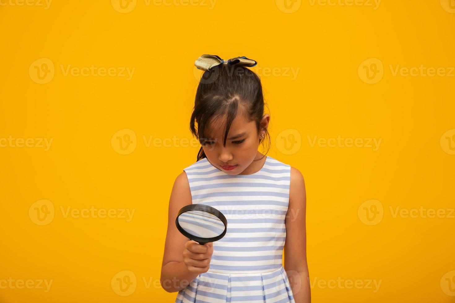 Portrait of happy little Asian child with magnifying glass. photo