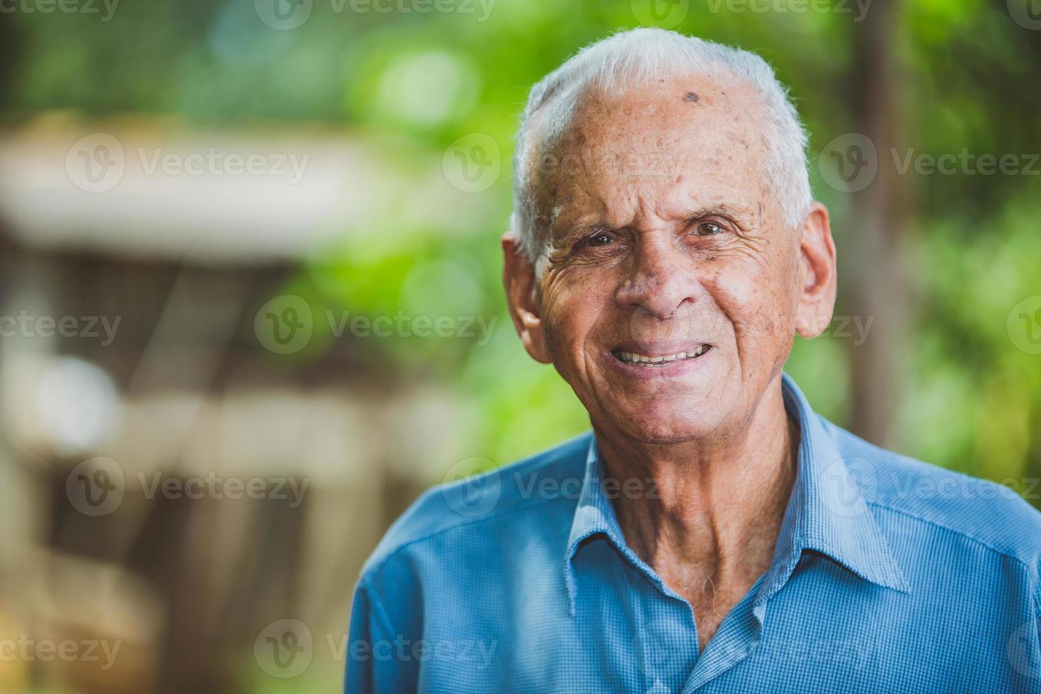 Portrait of smiling beautiful older male farmer. Elderly man at farm in summer day. Gardening activity. Brazilian elderly man. photo