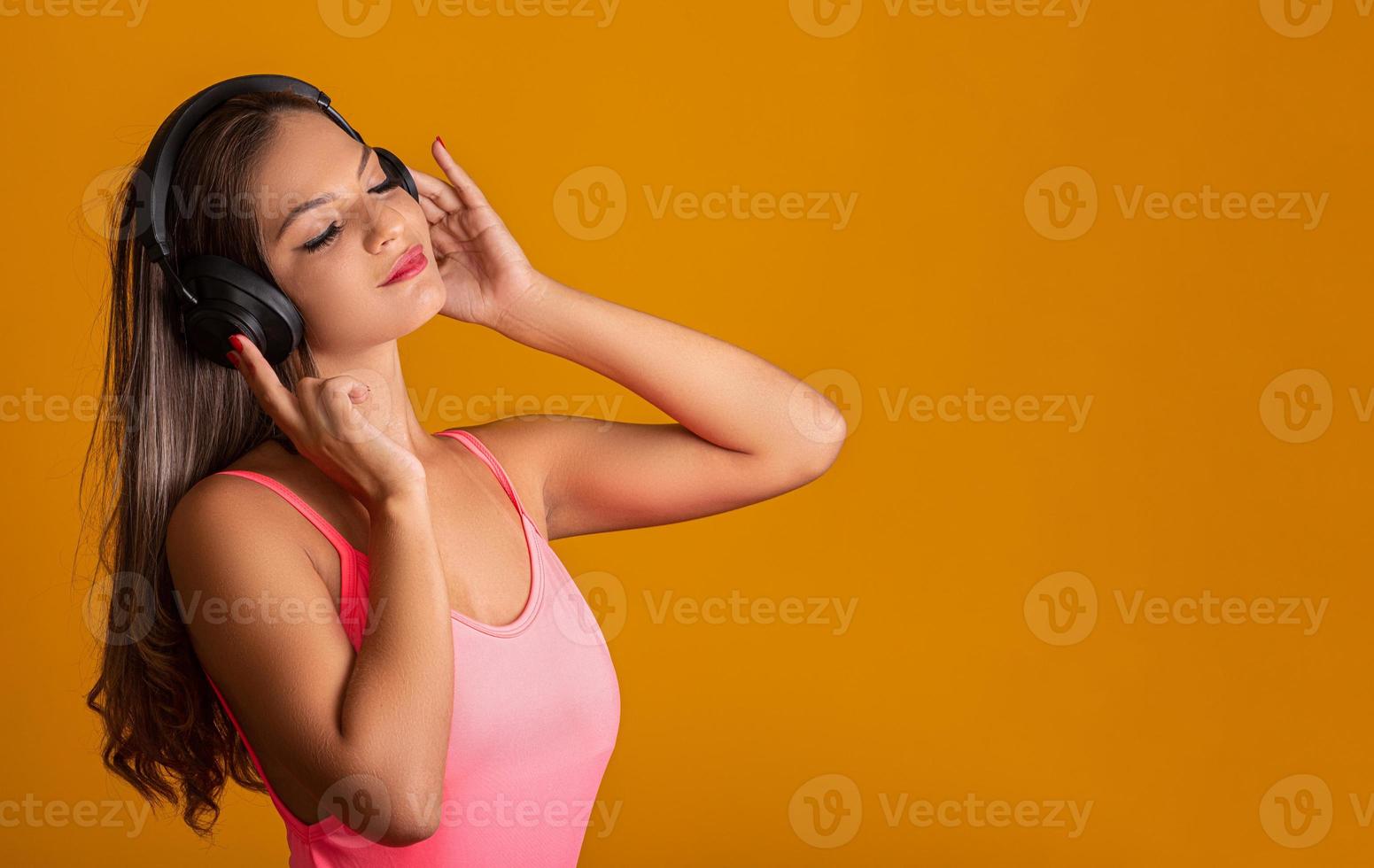 chica atractiva con auriculares sobre un fondo amarillo brillante. concepto de DJ foto