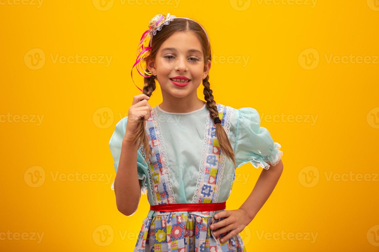 niño con ropa típica de la famosa fiesta brasileña llamada festa junina en celebración de sao joao. hermosa chica sobre fondo amarillo. foto