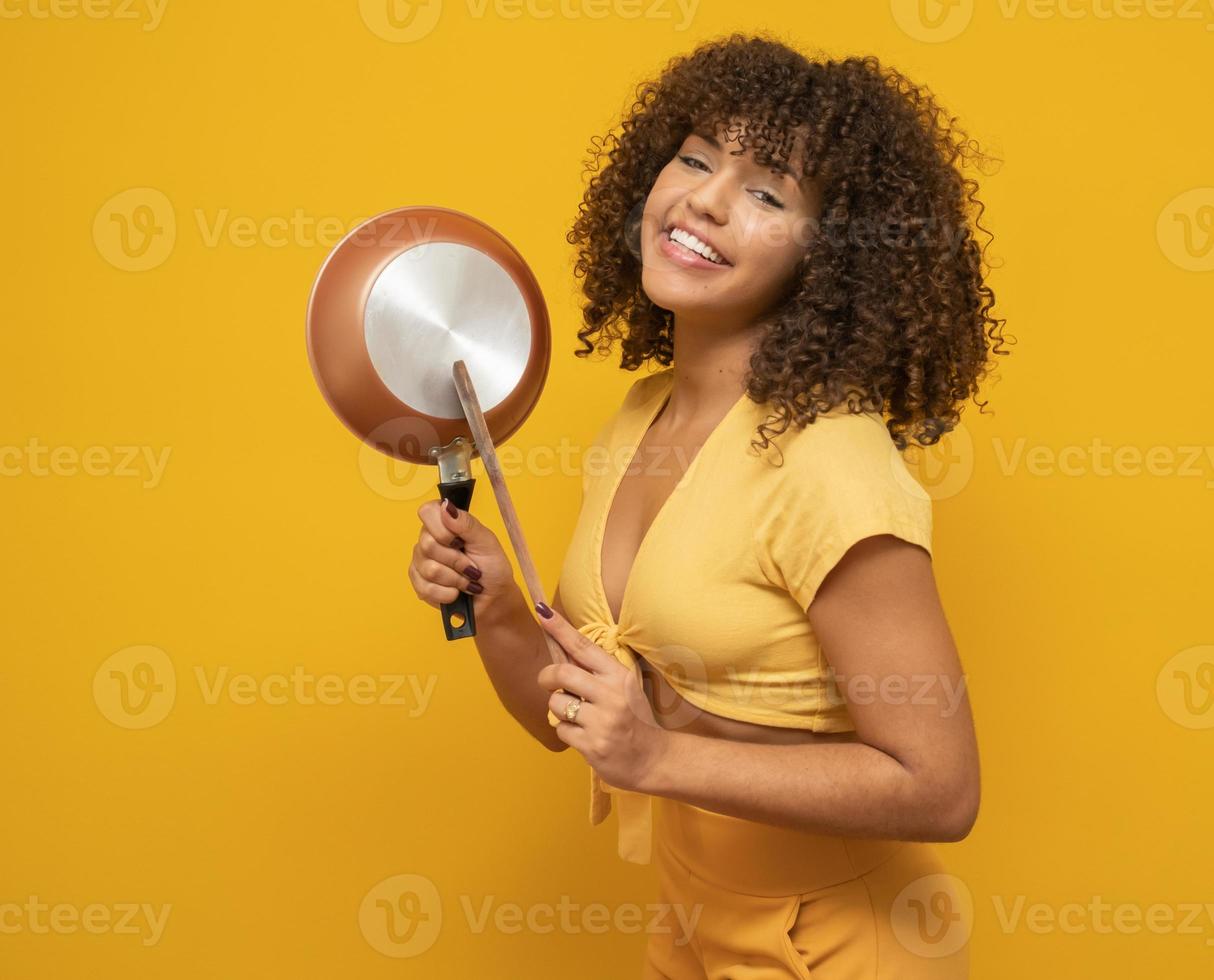 Cooking utensils. Cooking woman in kitchen with frying pan and wooden spoon. Housewife dancing. photo