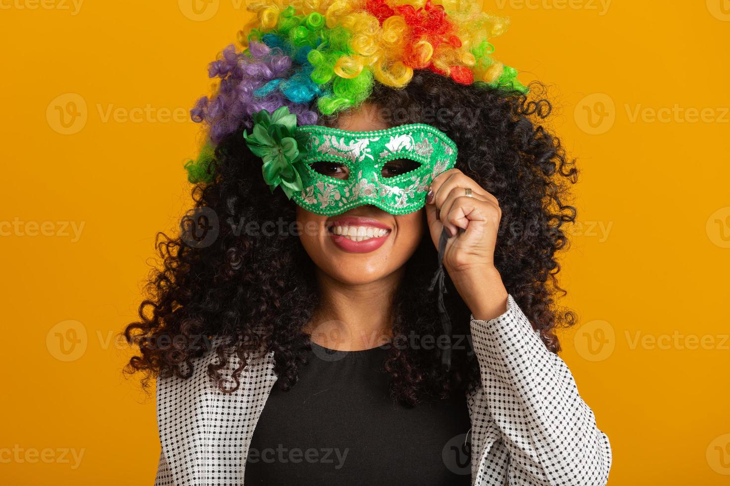 hermosa mujer vestida para la noche de carnaval. mujer sonriente lista para disfrutar del carnaval con una peluca y una máscara coloridas foto