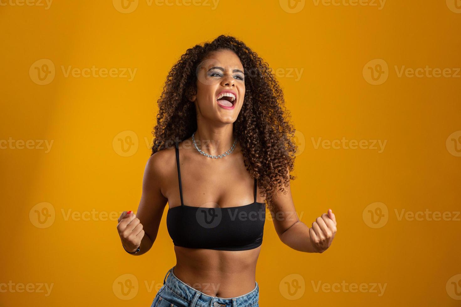 abrumada, emocionada, sonriente, feliz niña de pelo rizado afro celebrando noticias increíbles, logrando la victoria, ganando la competencia, ganando el gol o sucedió un evento afortunado inesperado. en amarillo foto