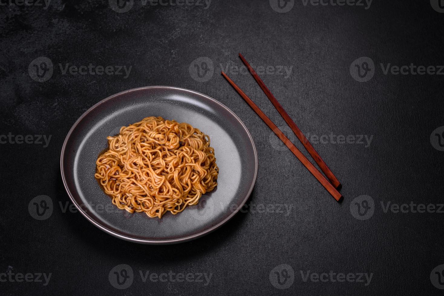 fideos de harina de trigo sarraceno con salsa, sésamo, hierbas y especias sobre un fondo de hormigón oscuro foto